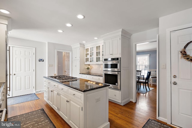 kitchen featuring hardwood / wood-style flooring, appliances with stainless steel finishes, a center island, tasteful backsplash, and white cabinets