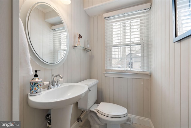 bathroom with sink, wooden walls, and toilet