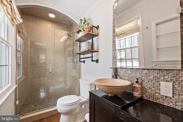 bathroom with vanity, toilet, a shower with door, and decorative backsplash