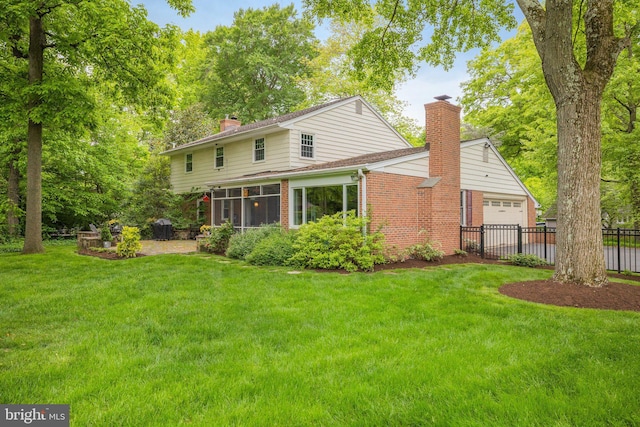 rear view of property with a sunroom, a lawn, and a garage