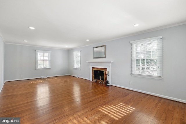 unfurnished living room featuring wood-type flooring, a brick fireplace, and crown molding