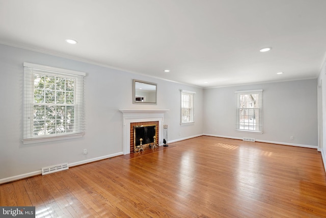 unfurnished living room with a brick fireplace, crown molding, and light hardwood / wood-style floors