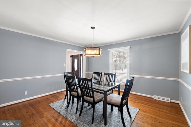 dining area with hardwood / wood-style flooring, ornamental molding, and a chandelier