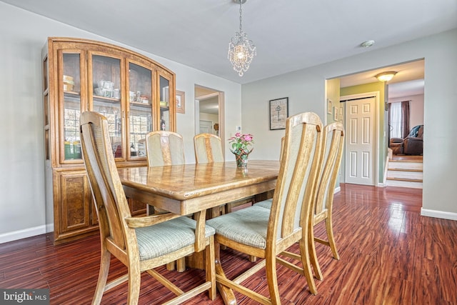 dining space with dark wood-type flooring and an inviting chandelier