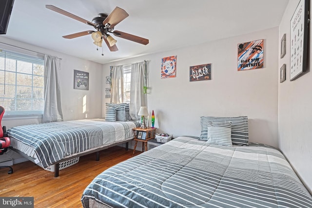 bedroom featuring multiple windows, hardwood / wood-style flooring, and ceiling fan