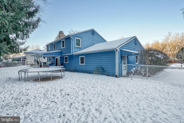 snow covered back of property featuring a trampoline