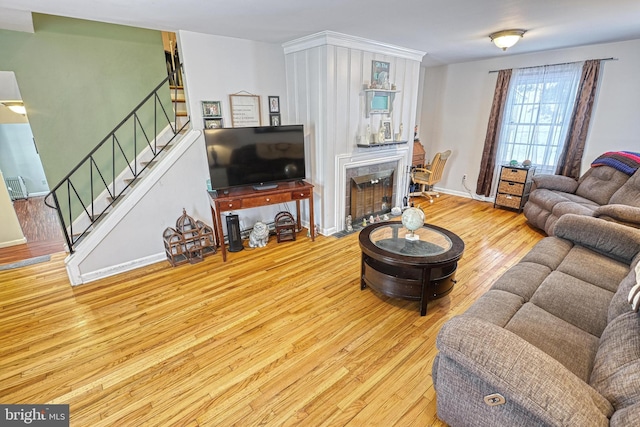 living room featuring a tiled fireplace and light wood-type flooring