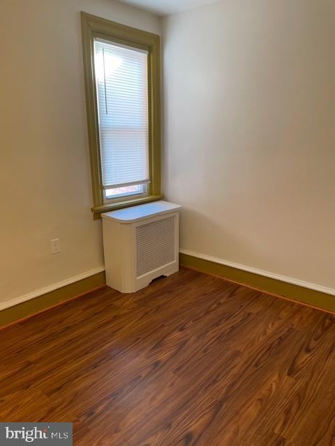 spare room featuring radiator heating unit and dark hardwood / wood-style floors