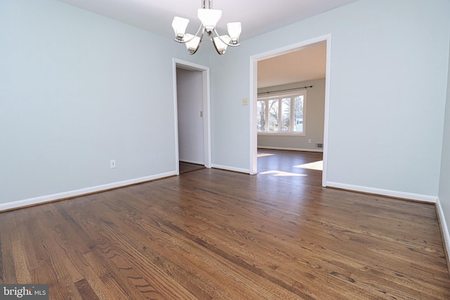 empty room with an inviting chandelier and dark hardwood / wood-style flooring