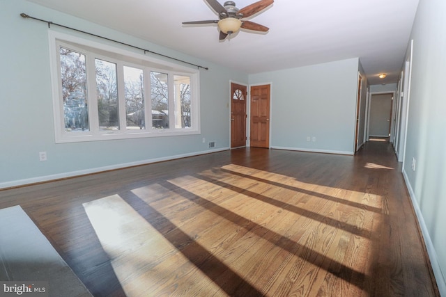 unfurnished living room featuring dark wood-type flooring and ceiling fan