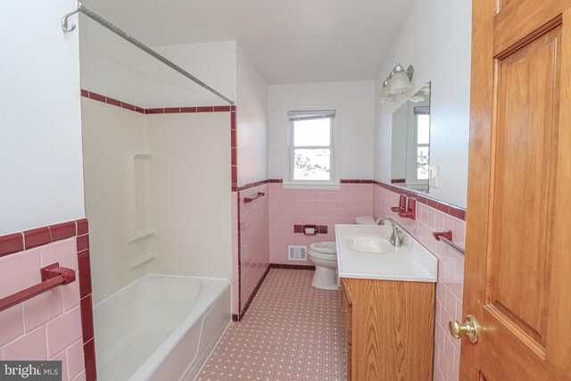 bathroom featuring vanity, toilet, and tile walls