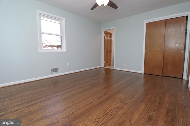 unfurnished bedroom with dark wood-type flooring, a closet, and ceiling fan