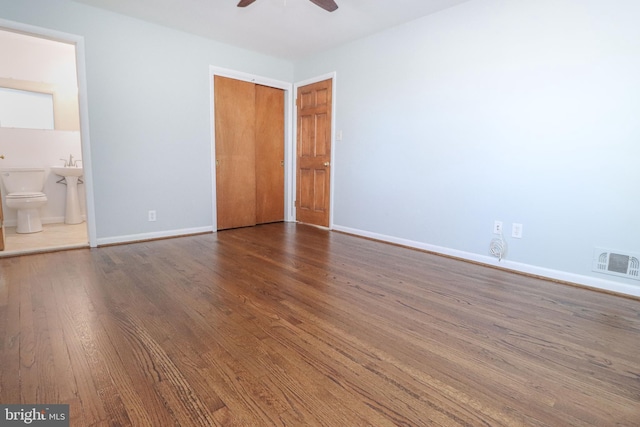 unfurnished bedroom featuring ensuite bath, wood-type flooring, and ceiling fan