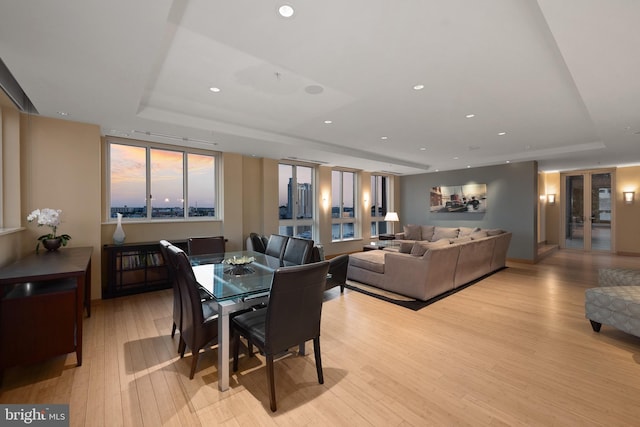 dining area with a tray ceiling and light hardwood / wood-style floors