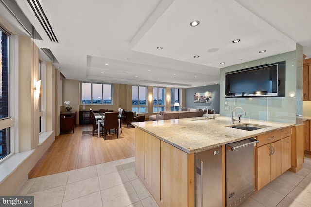 kitchen featuring sink, a center island with sink, light stone countertops, light tile patterned flooring, and light brown cabinets