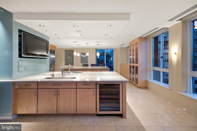 kitchen featuring sink, wine cooler, hanging light fixtures, light tile patterned floors, and light stone counters