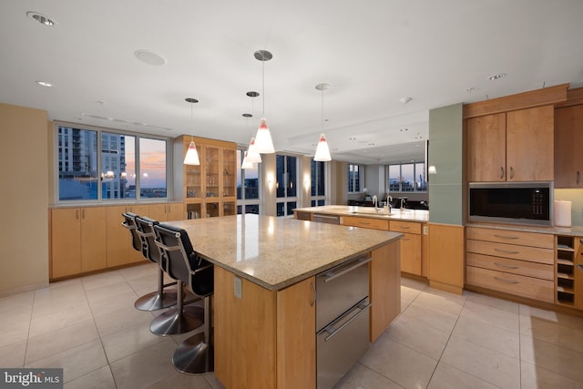 kitchen with hanging light fixtures, light tile patterned flooring, black microwave, and a kitchen island