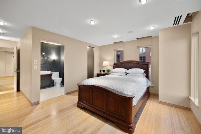 bedroom with ensuite bath and light hardwood / wood-style flooring