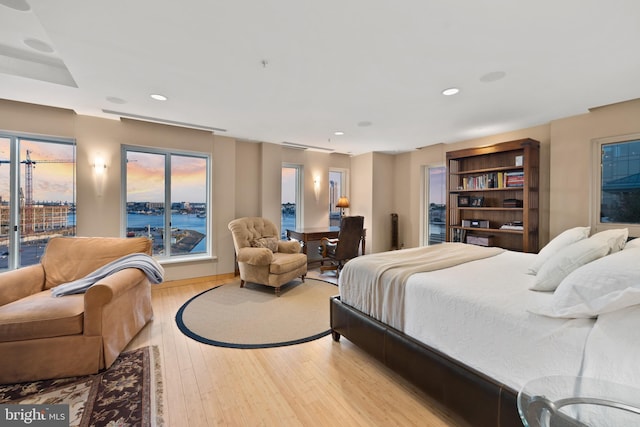 bedroom featuring a water view and light wood-type flooring