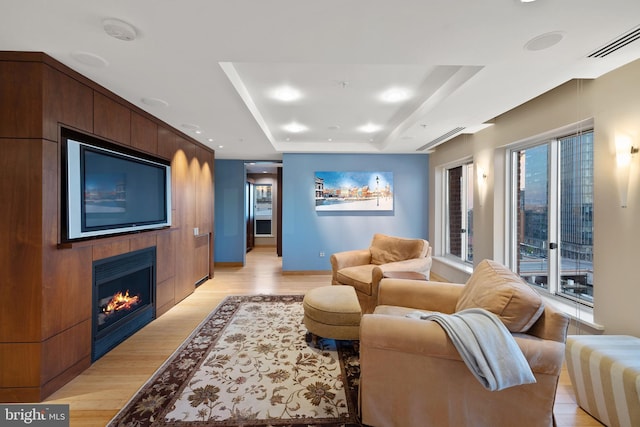 living room featuring a raised ceiling and light wood-type flooring