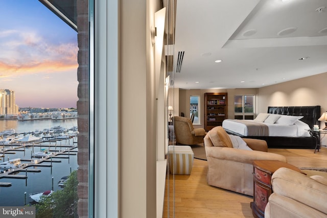 bedroom with light hardwood / wood-style flooring and a water view