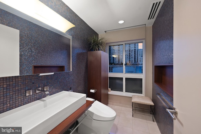 bathroom with sink, toilet, tile patterned flooring, and decorative backsplash