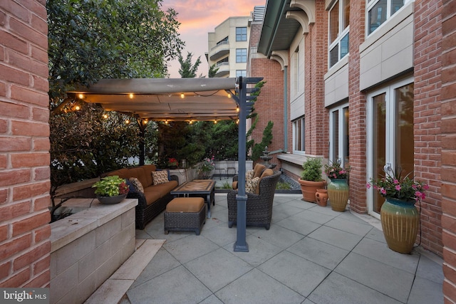 patio terrace at dusk with outdoor lounge area and a pergola