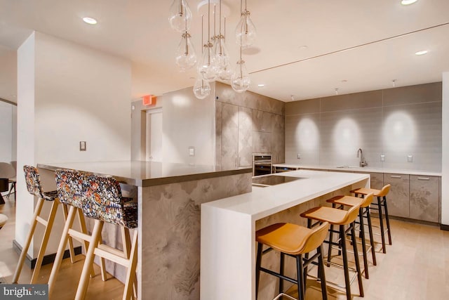 kitchen featuring pendant lighting, a breakfast bar area, tile walls, black electric stovetop, and kitchen peninsula