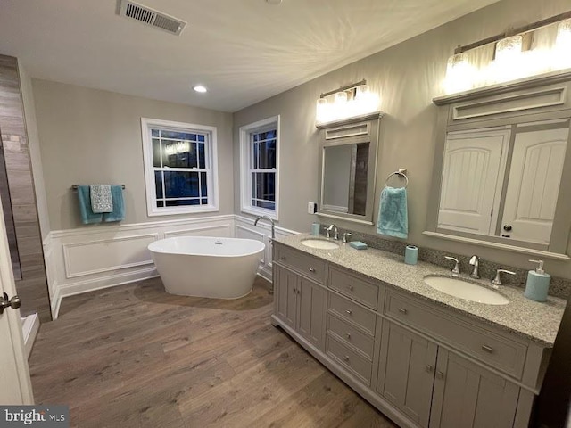 1394 B And A Blvd, Arnold, MD 21012 - bathroom featuring double vanity, a freestanding bath, wood finished floors, a wainscoted wall, and recessed lighting
