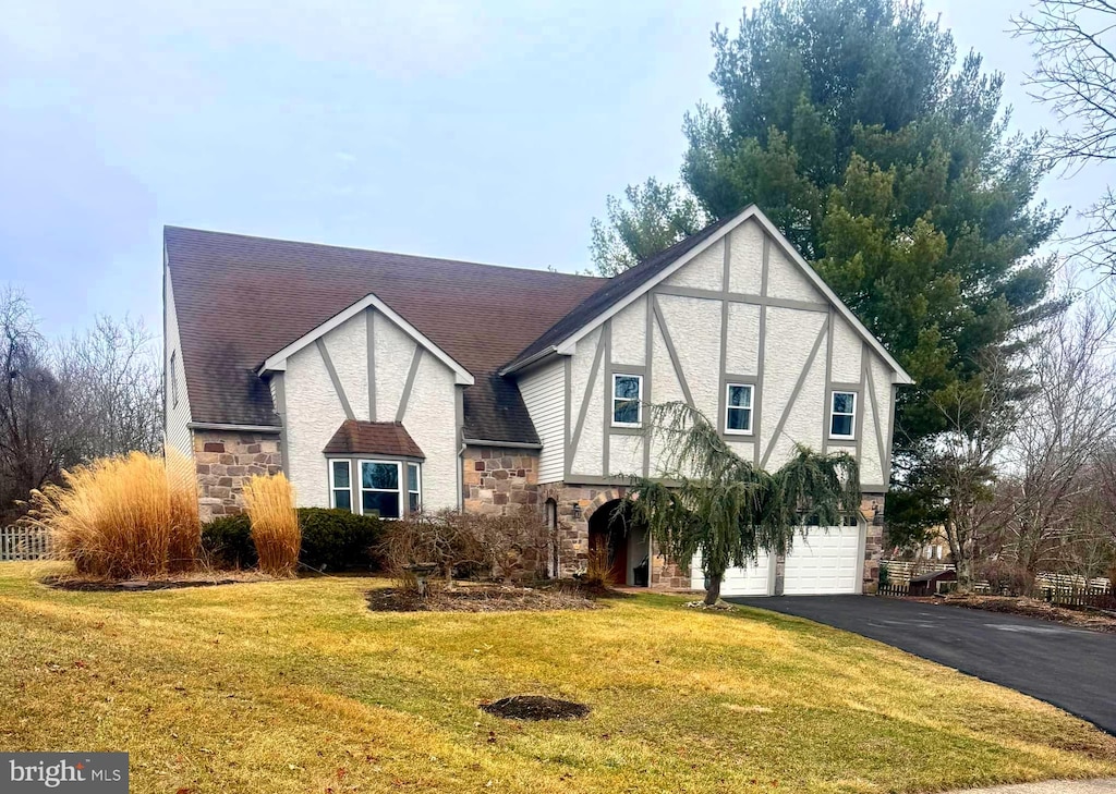 tudor home featuring a garage and a front lawn