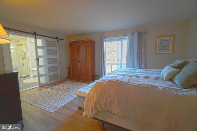 bedroom with a barn door, light hardwood / wood-style floors, and connected bathroom