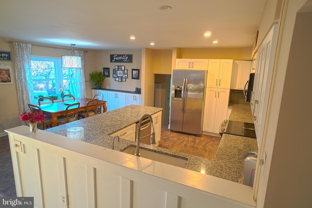 kitchen with sink, kitchen peninsula, white cabinets, and stainless steel refrigerator with ice dispenser