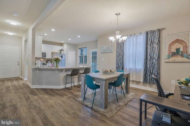 dining area with wood-type flooring, plenty of natural light, and a chandelier