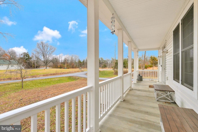 wooden terrace with central AC unit, a lawn, and a porch