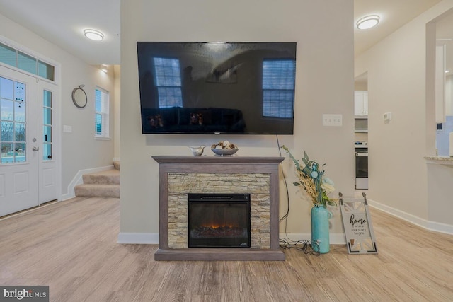 living room with a stone fireplace and light wood-type flooring