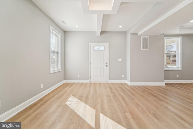 foyer featuring beamed ceiling, plenty of natural light, and light hardwood / wood-style floors