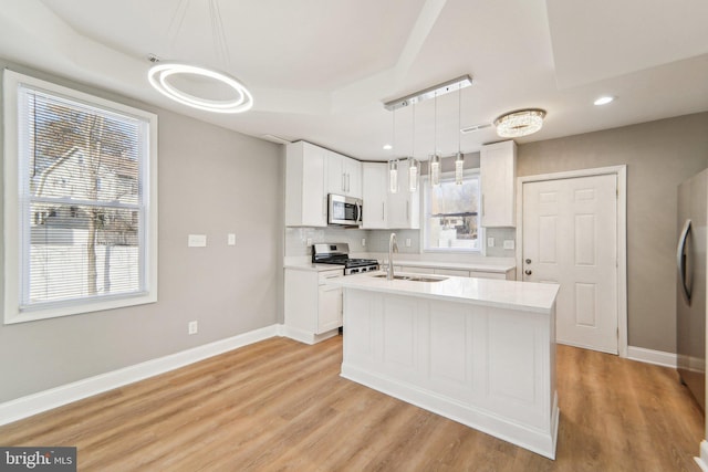 kitchen featuring pendant lighting, sink, white cabinetry, stainless steel appliances, and tasteful backsplash