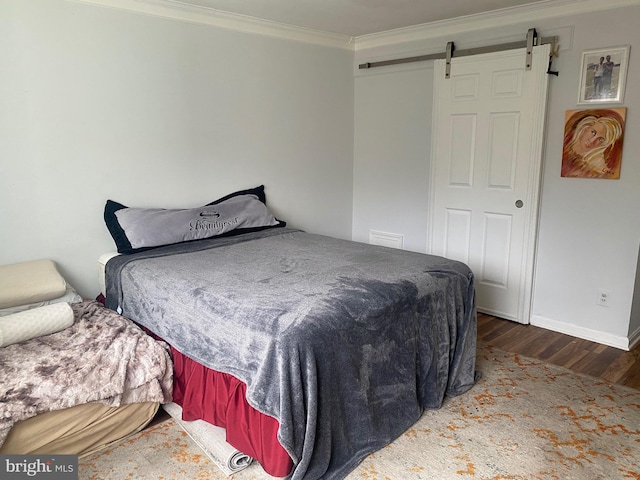 bedroom with ornamental molding, a barn door, and dark hardwood / wood-style floors