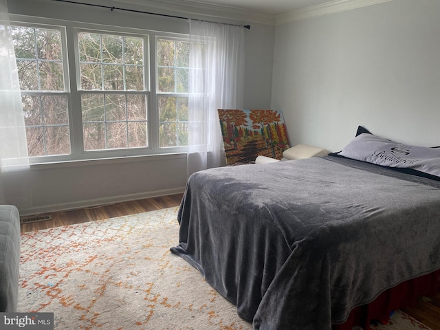 bedroom with multiple windows, ornamental molding, and hardwood / wood-style floors