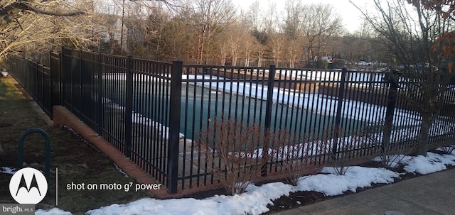 snow covered gate featuring a covered pool