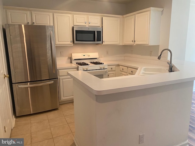 kitchen with sink, light tile patterned floors, stainless steel appliances, white cabinets, and kitchen peninsula