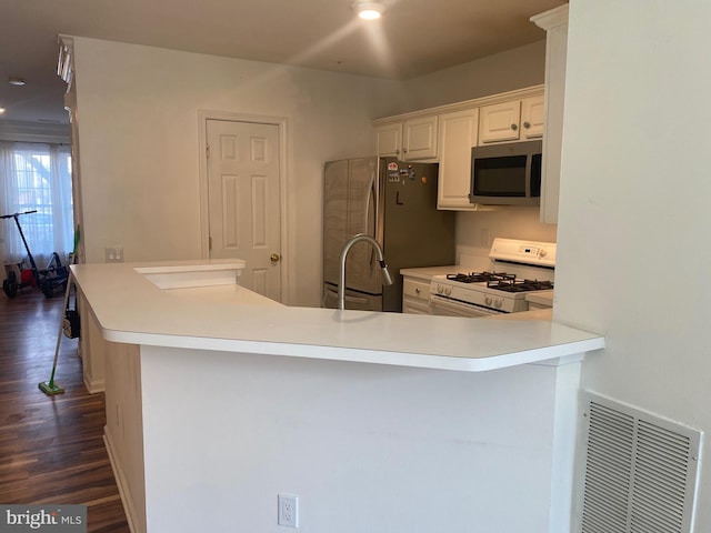 kitchen featuring white cabinetry, dark hardwood / wood-style floors, stainless steel appliances, and kitchen peninsula