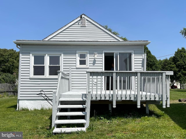 back of property with a wooden deck and a yard