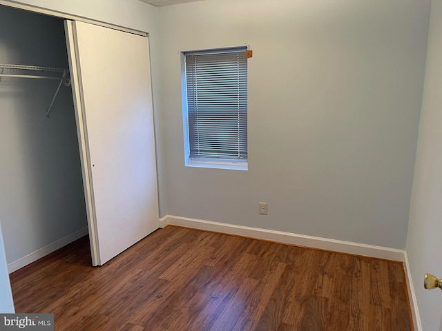 unfurnished bedroom with dark hardwood / wood-style flooring and a closet