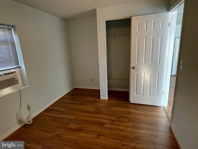 unfurnished bedroom featuring dark wood-type flooring, a closet, and cooling unit