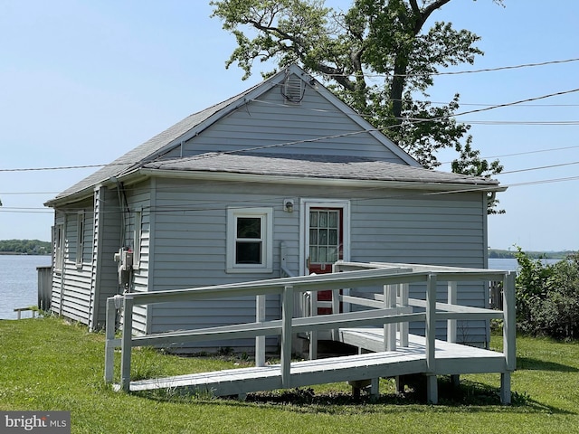 rear view of property with a deck with water view and a yard