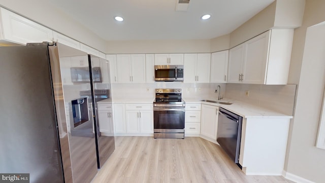 kitchen with backsplash, stainless steel appliances, sink, and white cabinets