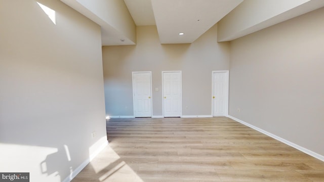 interior space featuring a towering ceiling and light hardwood / wood-style floors