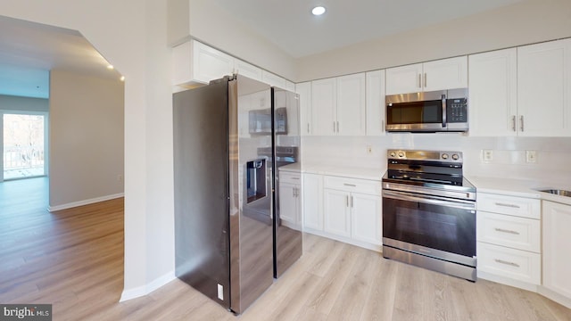 kitchen with white cabinetry, appliances with stainless steel finishes, sink, and light hardwood / wood-style floors