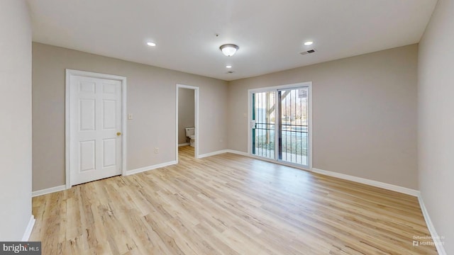 unfurnished bedroom featuring ensuite bath, access to exterior, and light wood-type flooring